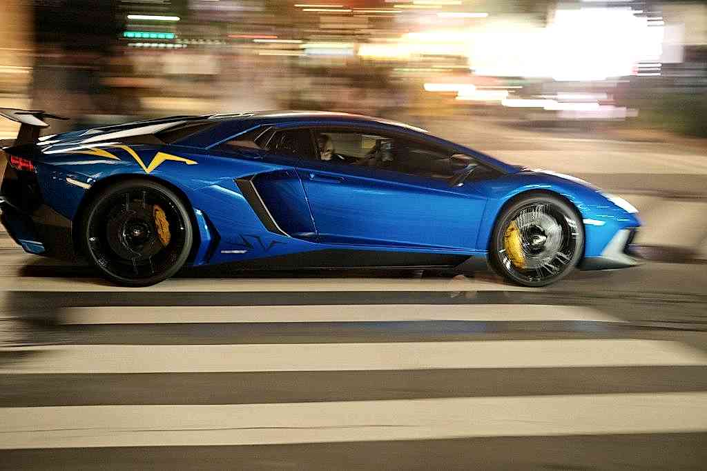 A blue sports car driving down a city street