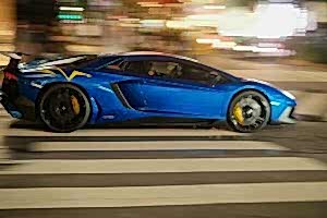 A blue sports car driving down a city street